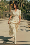 Woman in a floral dress walking outdoors on a sunny day.