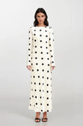 Woman wearing a long polka dot dress on a white background