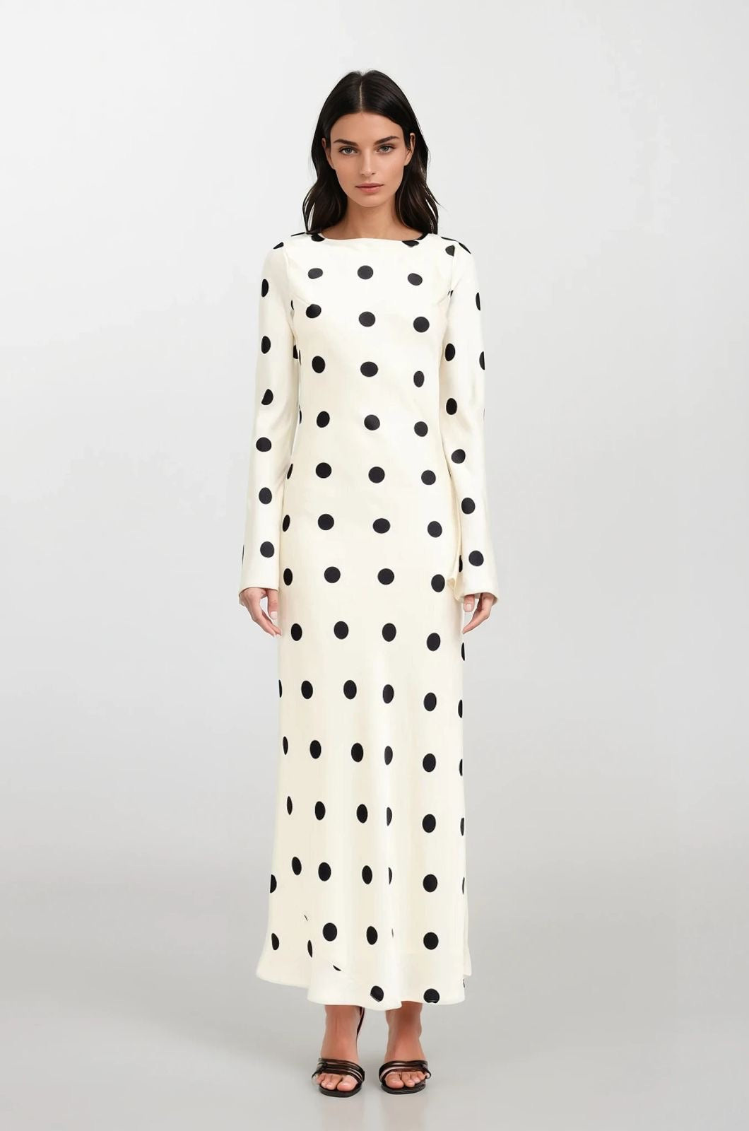 Woman wearing a long polka dot dress on a white background