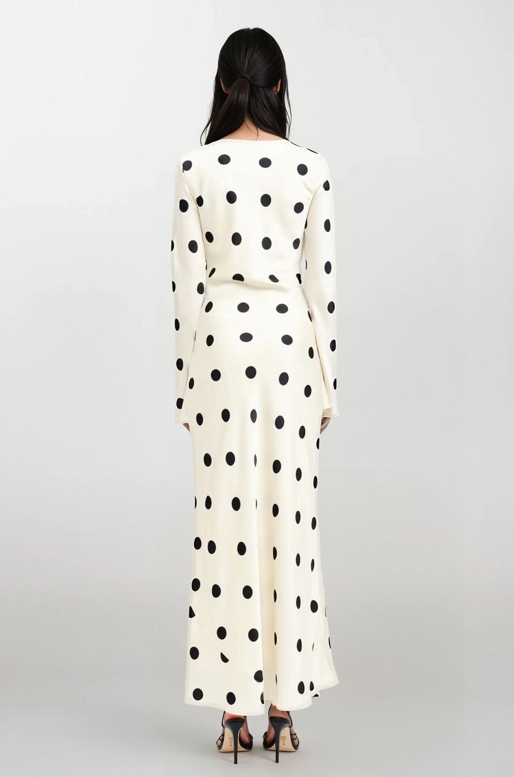 Woman wearing a long polka dot dress on a white background