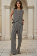Woman wearing a gray jumpsuit standing in front of classical architecture.