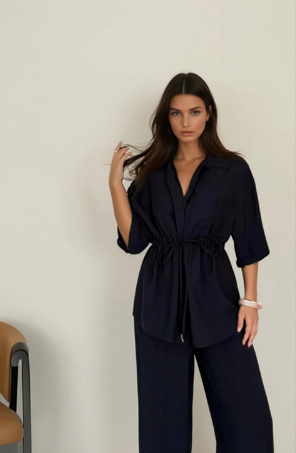 Woman wearing a navy blue outfit against a plain background