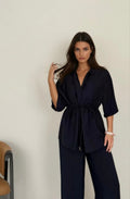 Woman wearing a navy blue outfit against a plain background
