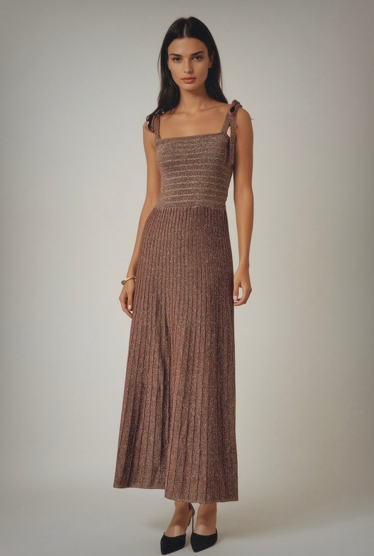 Woman wearing a brown patterned dress against a plain background
