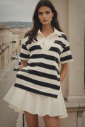 Woman wearing a black and white striped dress standing on a city street.