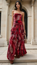Woman in a strapless red floral dress standing in front of classical architecture.